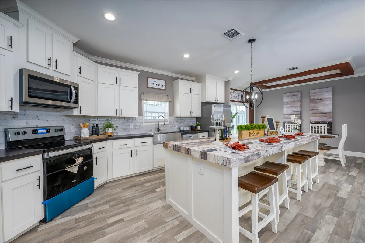 White kitchen with a long island, stainless appliances and a pendant light